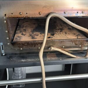 Vista d'insieme della facciata in acciaio inox del forno prima dell'intervento. Si nota l'effetto brunito e opaco localizzato intorno alla bocca del forno e sui rivetti.