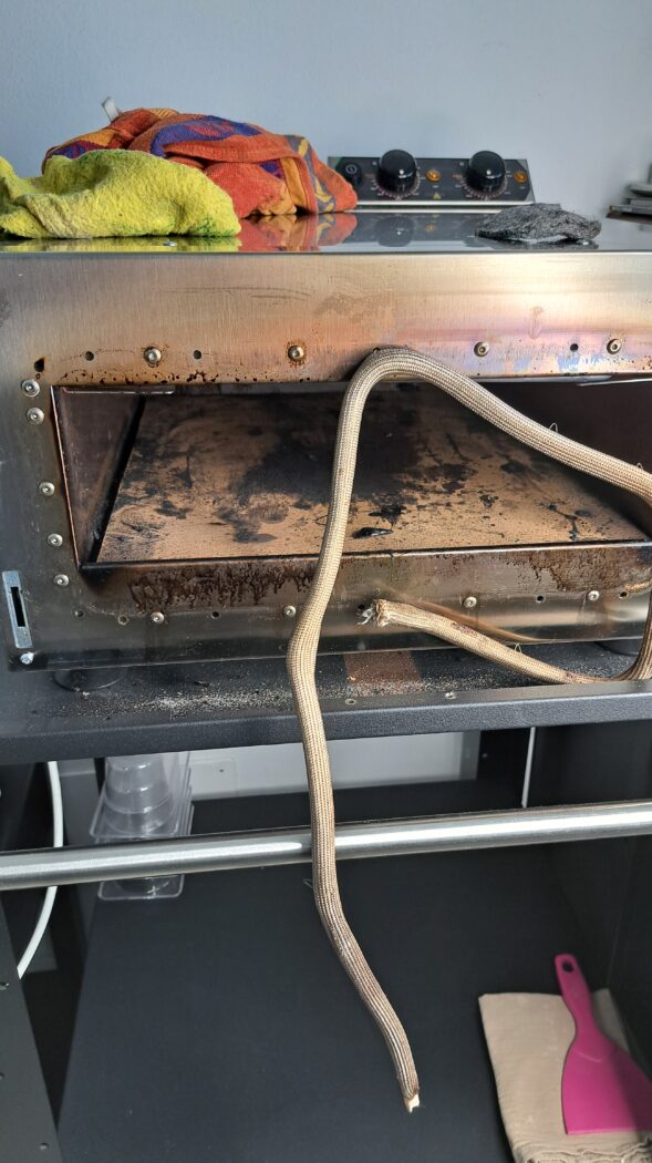 Vista d'insieme della facciata in acciaio inox del forno prima dell'intervento. Si nota l'effetto brunito e opaco localizzato intorno alla bocca del forno e sui rivetti.